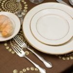 Elegant flatware setting with silver plate forks and knives, accompanied by fine china plates and a bread roll on a decorative tablecloth, ideal for weddings and events in Little Rock, AR.