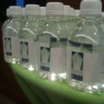 Water bottles Personalized water bottles lined up on a green table, showcasing branding for event beverage service.