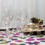 Elegant glassware rental display featuring multiple stemmed glasses alongside a silver serving tray with fruit, set on a colorful tablecloth, ideal for enhancing event aesthetics.