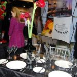Elegant table setting featuring fine glassware rentals, including wine glasses and hi-ball glasses, complemented by a decorative floral centerpiece, showcasing options for events like weddings and banquets.