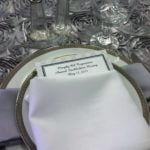 Elegant table setting featuring a menu card placed on a decorative plate, accompanied by a neatly folded napkin, ideal for wedding and event printing services.
