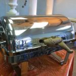 serving pieces 2 Silver food warmer with a shiny exterior, designed to keep dishes hot, displayed on a table, relevant for event catering and food service rentals.