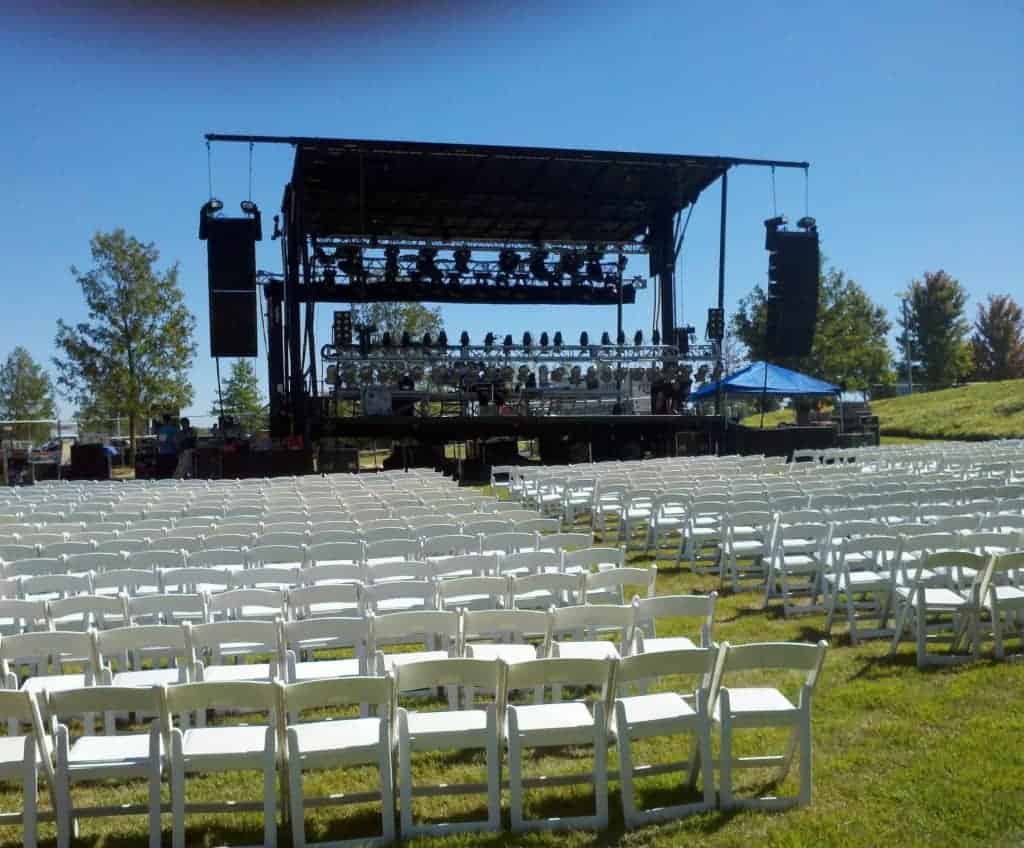Outdoor concert setup featuring rows of white chairs in front of a stage at the William J Clinton Presidential Library, with sound equipment and lighting ready for the Chicago Concert on September 24, 2011.