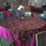 Round table with a decorative shantung swirl tablecloth, vibrant pink and brown colors, and a floral centerpiece, set in an event space showcasing rental options for parties and ceremonies in Little Rock, AR.