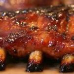 Close-up of grilled barbecue ribs, showcasing a caramelized glaze, emphasizing the delicious results of using rental grills for events in Arkansas.