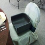 Booster seat placed on a standard folding chair, suitable for children's seating at events, highlighting rental options for parties and gatherings.