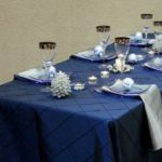 Table set with elegant navy blue chevron linen, adorned with glassware, candles, and decorative accents, showcasing a sophisticated event setup for Party Time Rental and Events.