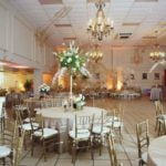 Elegant gold Chiavari chairs arranged around tables in a beautifully decorated event space, showcasing a sophisticated atmosphere for weddings and special occasions.