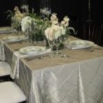 Elegant rectangular banquet table set with textured linen, floral centerpieces, and fine tableware, ideal for event decoration and table setting.
