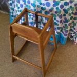 Wooden high chair for children beside a polka-dotted tablecloth, highlighting essential event rentals for family gatherings and parties.