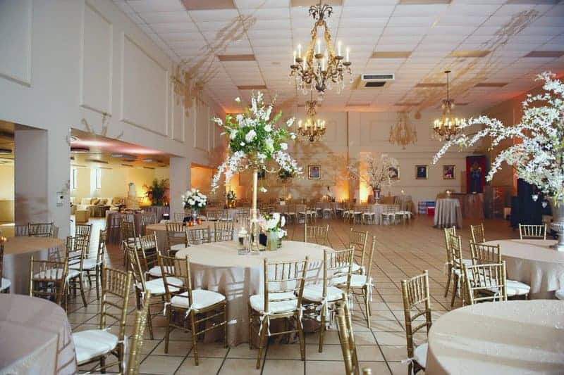 Elegant ballroom setup for a wedding at Cathedral of St Andrew, featuring gold Chiavari chairs, round tables with beige linens, and floral centerpieces by Jessica Kersey, Finishing Touch Events.