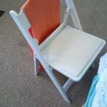 White garden chair with orange cushion, suitable for wedding and event rentals, showcasing a classic design and sturdy construction.