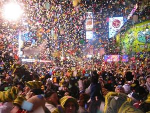 Crowd celebrating New Year's Eve in Times Square, surrounded by colorful confetti and festive atmosphere, representing a lively party scene for New Year's celebrations.